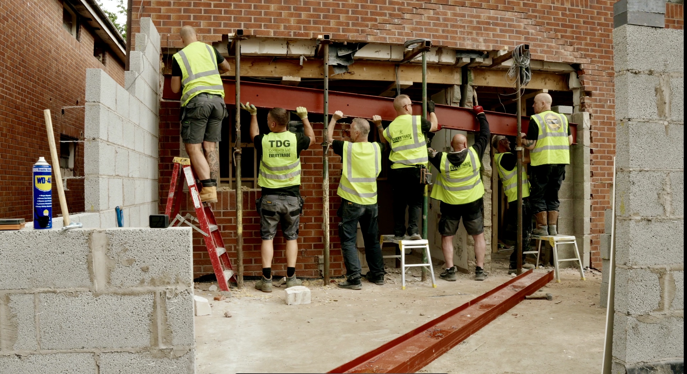 A picture of EveryTrade construction workers working on site, adding a metal structural beam to a property